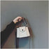 White mini crossbody bag held by its top handle