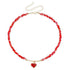 Red irregular bead necklace with red heart pendant and gold-tone fittings, on white