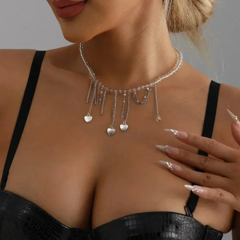 Pale beaded necklace with dangling silver-tone chains and small heart charms, modeled