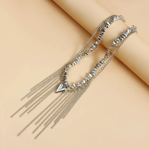Silver-tone beaded fringe necklace laid diagonally across a beige prop