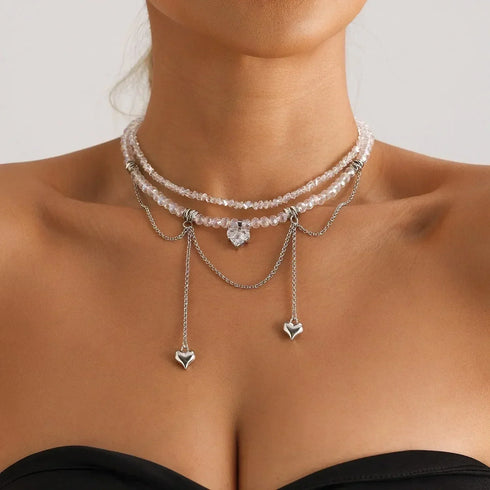 Layered pale beaded necklace with heart drops and draped chains, modeled front view