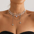 Layered pale beaded necklace with heart drops and draped chains, modeled front view