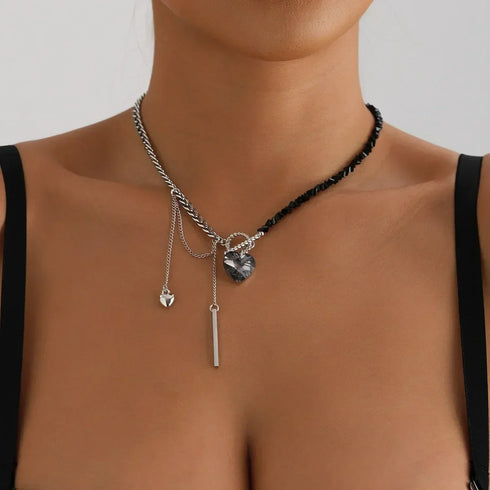 Asymmetric black and silver-tone beaded necklace with large dark heart, worn