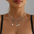 Multiple small heart drops suspended from a pale necklace, centered model view