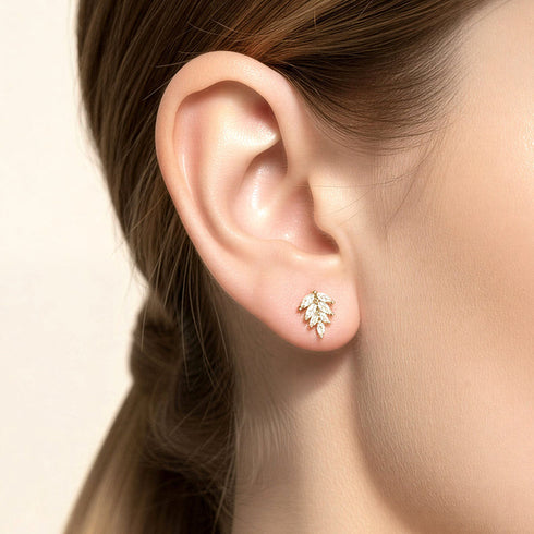 Gold-tone CZ leaf stud earring worn on an ear