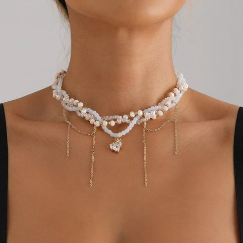 White layered necklace with gold-tone drops and small center heart, worn