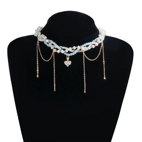 White layered bead and gold-tone chain necklace displayed on a black bust