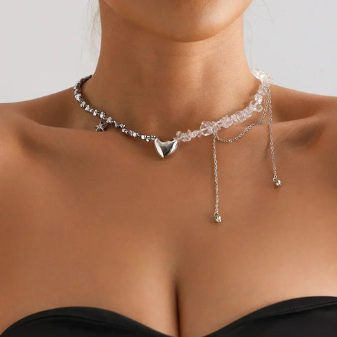 Asymmetric pale bead necklace with large silver-tone heart and chain drops, worn