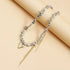 Pointed heart pendant necklace and chain drops displayed on a beige prop
