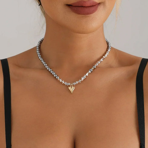 Silver-tone single bead strand with small gold-tone pointed heart, front neckline view