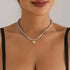 Silver-tone single bead strand with small gold-tone pointed heart, front neckline view