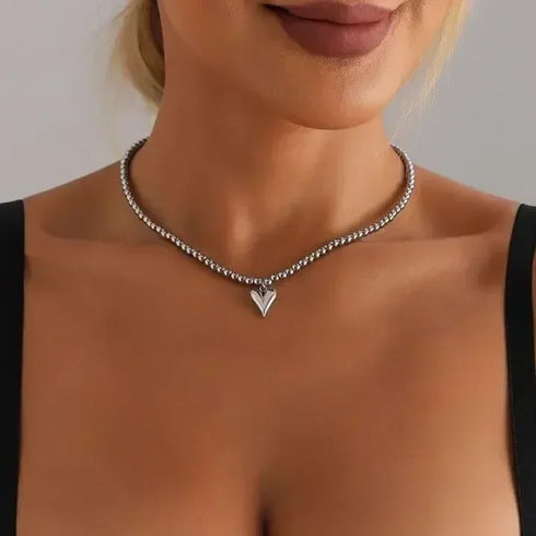 Single silver-tone beaded necklace with small pointed heart, worn close to the neck