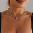 Single silver-tone beaded necklace with small pointed heart, worn close to the neck
