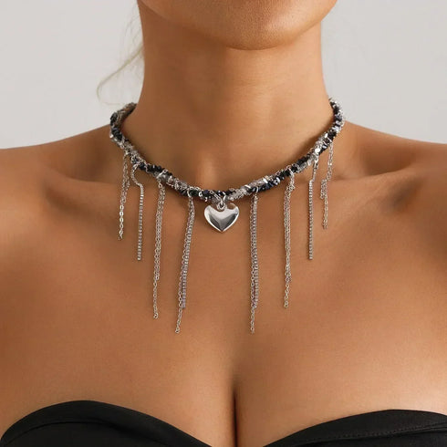 Dark beaded necklace with silver-tone heart and hanging chain fringe, worn