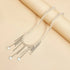 Heart-drop necklace with pale beads laid out on a beige prop