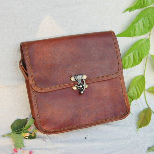 Close front view of brown leather flap bag and brass clasp