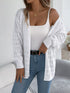 White crochet-knit cardigan, draped off one shoulder to show sleeve texture