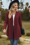 Burgundy textured long cardigan worn open with a black hat