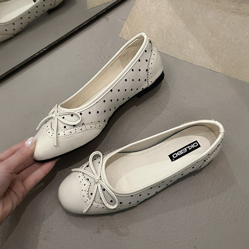 Close-up of beige ballet flats showing bow and perforated upper