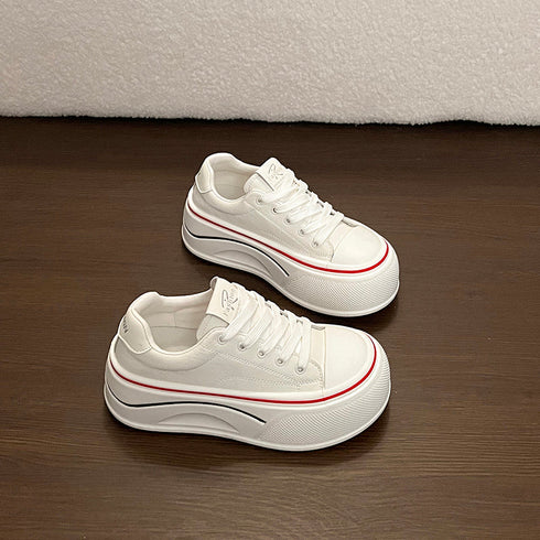 White platform sneakers shown from front and side on a brown floor