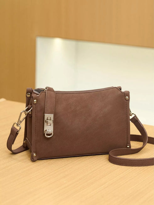 Brown Buckle-Detail Crossbody Bag: Brown bag with long strap laid beside it