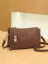 Brown Buckle-Detail Crossbody Bag: Brown bag with long strap laid beside it