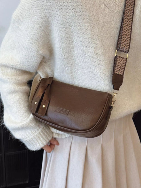 Coffee brown crossbody bag shown at an angle near the hip