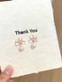 Flower pearl-drop earrings displayed on a card held in a hand