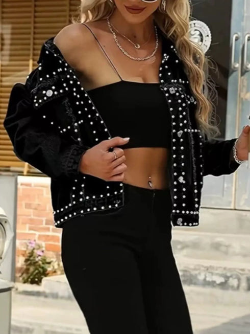 Black studded denim jacket worn off one shoulder, showing the button front and raw hem