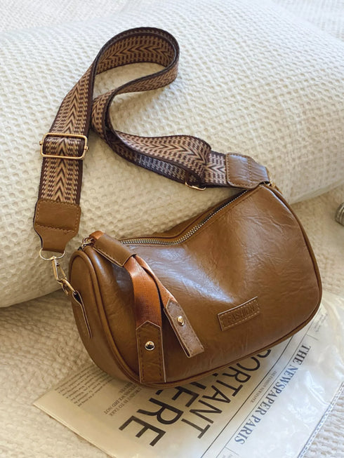 Brown retro bag with patterned strap resting on a book
