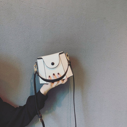 White mini bucket bag with black edging and curved front flap