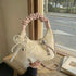 Cream mini purse with pink handle displayed beside a chair