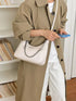Chain-Detail Shoulder Bag: White chain-detail bag worn with beige coat, front view