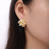 Shell Pearl Stud Earrings: Gold-tone white-bead stud earring worn, close-up