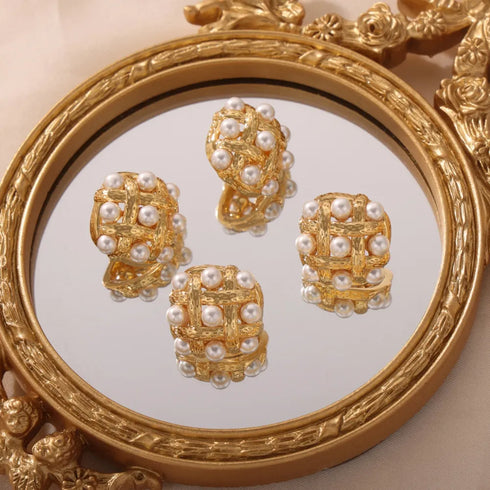 Shell Pearl Stud Earrings: Gold-tone white-bead stud earrings displayed on ornate mirror