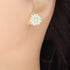 White daisy stud earring worn on ear, showing floral design and pearl-look center