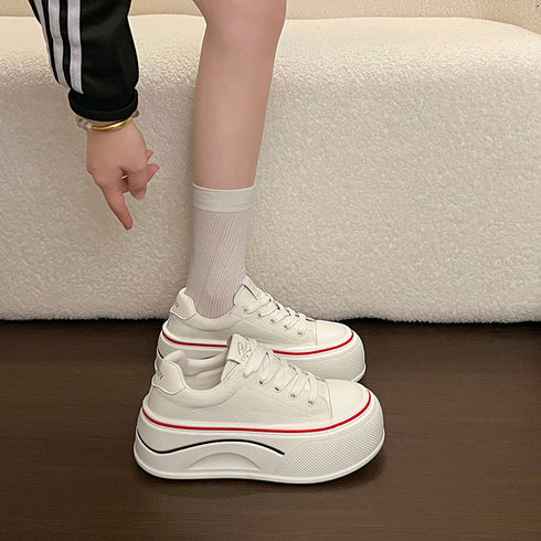 Side view of white platform sneakers worn with white socks, showing the sculpted sole