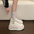 Side view of white platform sneakers worn with white socks, showing the sculpted sole