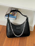 Chain-Detail Shoulder Bag: Black shoulder bag with silver-tone chain displayed on wooden table