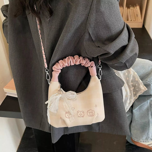 Cream bow-detail mini purse with pink handle, closer worn view