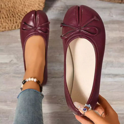 Top view of burgundy flats with one shoe worn and one held