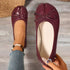 Top view of burgundy flats with one shoe worn and one held