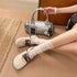 Beige lace-up ballet flats styled with white socks and a patterned handbag