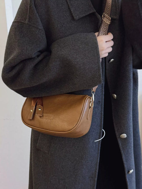 Brown faux leather crossbody bag worn with a dark coat