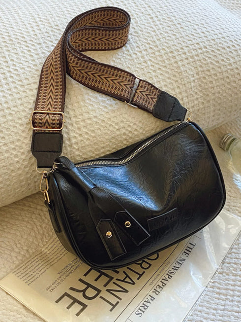 Black crossbody bag and patterned strap resting on a book