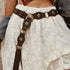 Brown Western studded faux leather belt worn over a white lace skirt