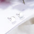 Front view of polished sterling silver heart studs with posts resting on a white card