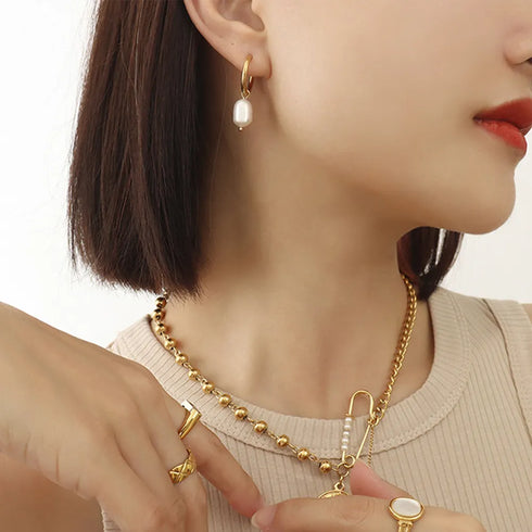 Freshwater pearl hoop earring worn on a model with layered necklaces