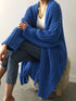 Blue chunky longline cardigan worn open over a white top, seated view