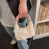 Top-handle view of cream mini purse with decorative bow